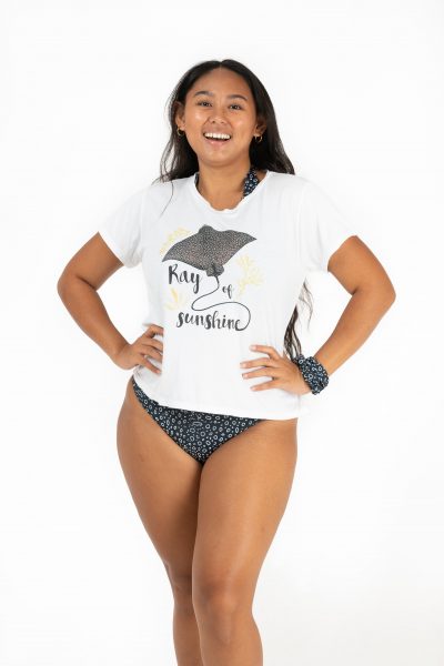 woman wearing a spotted eagle ray design t-shirt that says 'Ray of sunshine' under an illustration of a spotted eagle ray