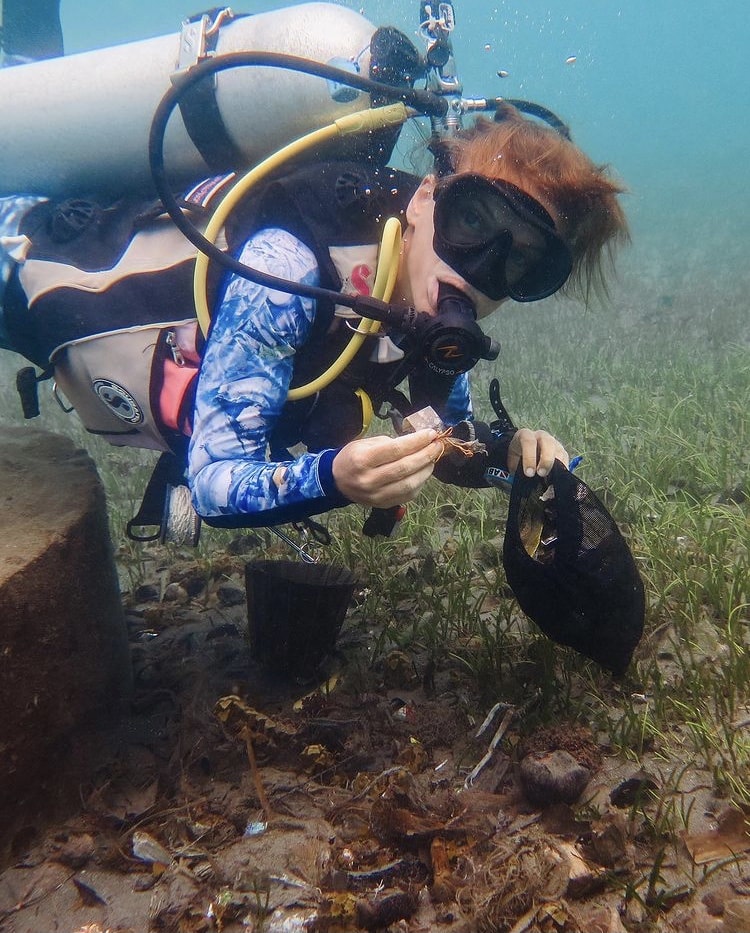 woman picking up trash on an underwater cleanup